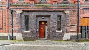 A brick building with a wooden door, two windows, and a paved entrance area. - Cozy 2-bedroom apartment in welcoming Liverpool with WiFi (Liverpool)