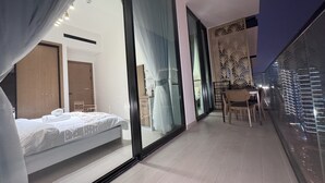A modern hotel room with a large bed, a small table with chairs, and a balcony with a railing. - Royal 2-Bedroom Apt with Private Pool in Dubai (Dubai)
