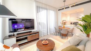 A modern living room with a flat-screen TV, a dining area, and a kitchen in the background. - Royal 2-Bedroom Apt with Private Pool in Dubai (Dubai)