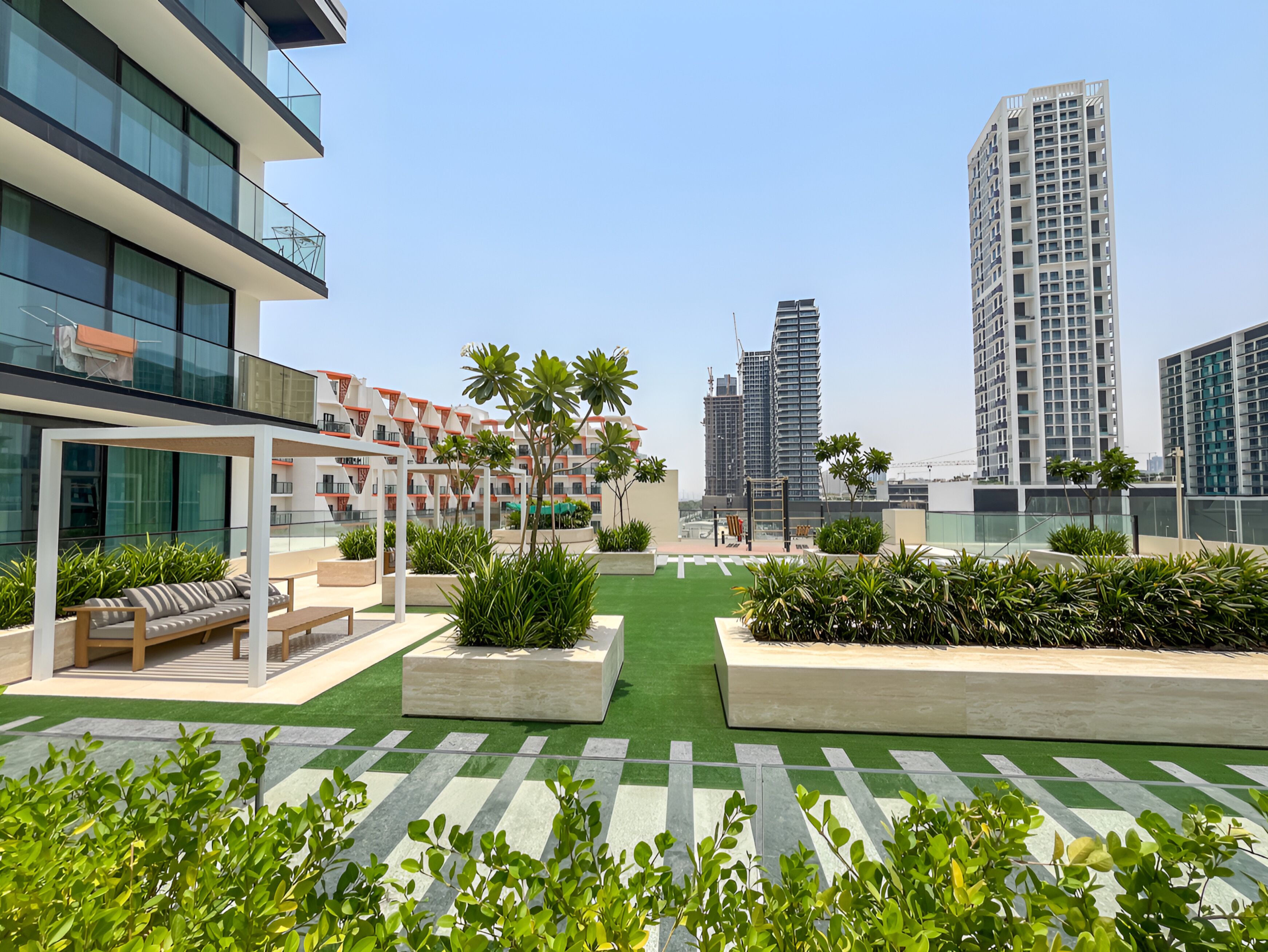 A rooftop garden with seating areas, planters, and a view of surrounding high-rise buildings.