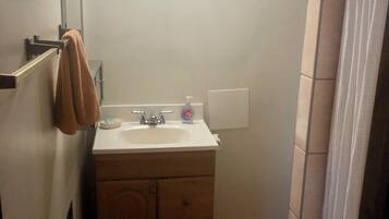 A bathroom with a sink, mirror, towel rack, and shower curtain.