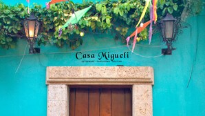Una puerta de madera con un letrero que dice "Casa Migueli" y la ubicación "Getsemaní, Cartagena, Colombia".