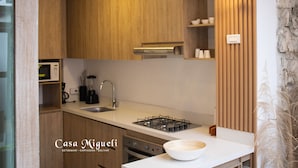 Una cocina moderna con armarios de madera, estufa a gas, lavamanos y luces colgantes.