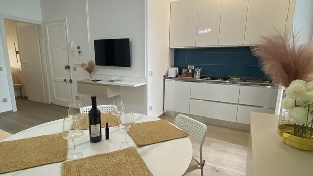Cuina moderna amb armaris blancs, forn integrat i zona de menjador amb taula rodona i caires.