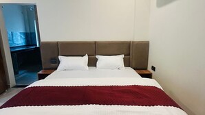 A hotel room with a large bed, a red blanket, a brown headboard, and a white wall. - A Charming Place To stay In Tapovan Rishikesh, Away from Hustle And Bustle (Rishikesh)