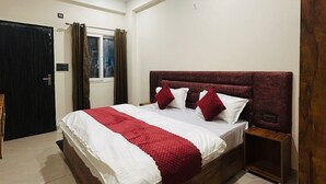 A bedroom with a bed, a ceiling fan, a nightstand, and a door. - A Charming Place To stay In Tapovan Rishikesh, Away from Hustle And Bustle (Rishikesh)