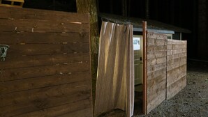 Une structure en bois comprenant un banc et une porte, qui pourrait servir d’espace de rangement ou d’abri utilitaire.