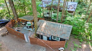 Une petite cabane en bois, surmontée d’un toit en métal, entourée d’arbres.
