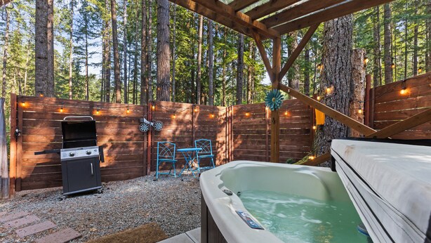 Une terrasse en bois avec un jacuzzi, un barbecue et des chaises bleues.