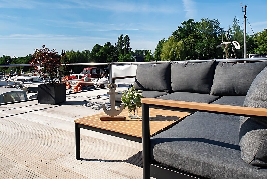 Eine Dachterrasse mit einer Sitzecke, einem Holztisch und einem Blumentopf.