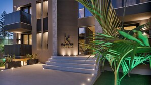 A modern building with a sign reading "KARERIIS LUXURY SITES," featuring a staircase leading to the entrance, a balcony, and a well-lit exterior.
