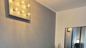 Een moderne kamer met een zwarte tv-standaard, een eettafel met stoelen en een wandlamp.