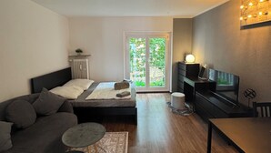Een moderne, compacte leefruimte met een bed, een bank en een eethoek.
