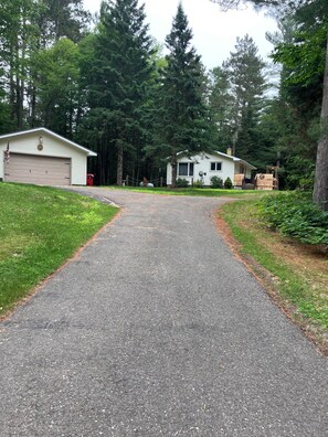 Une allée menant à une maison avec un garage et un petit abri de jardin.