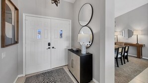 Un corridoio con una porta doppia, un tappeto decorato, un armadietto e uno specchio.
