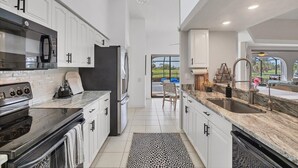 Una cucina moderna con mobili bianchi, un'isola centrale e vista sull'esterno.
