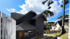 Een modern huis met een grijs dak, een klein portaaltje en een omheind gazon.