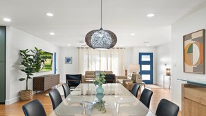 A modern dining room with a glass table, black chairs, a hanging light fixture, and a view of a tennis court through the window. - 5 min to Old Town, Pool & Spa, 2 King Suites (Scottsdale)
