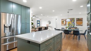 A modern kitchen with a central island, stainless steel appliances, and a dining area with a glass table and chairs. - 5 min to Old Town, Pool & Spa, 2 King Suites (Scottsdale)