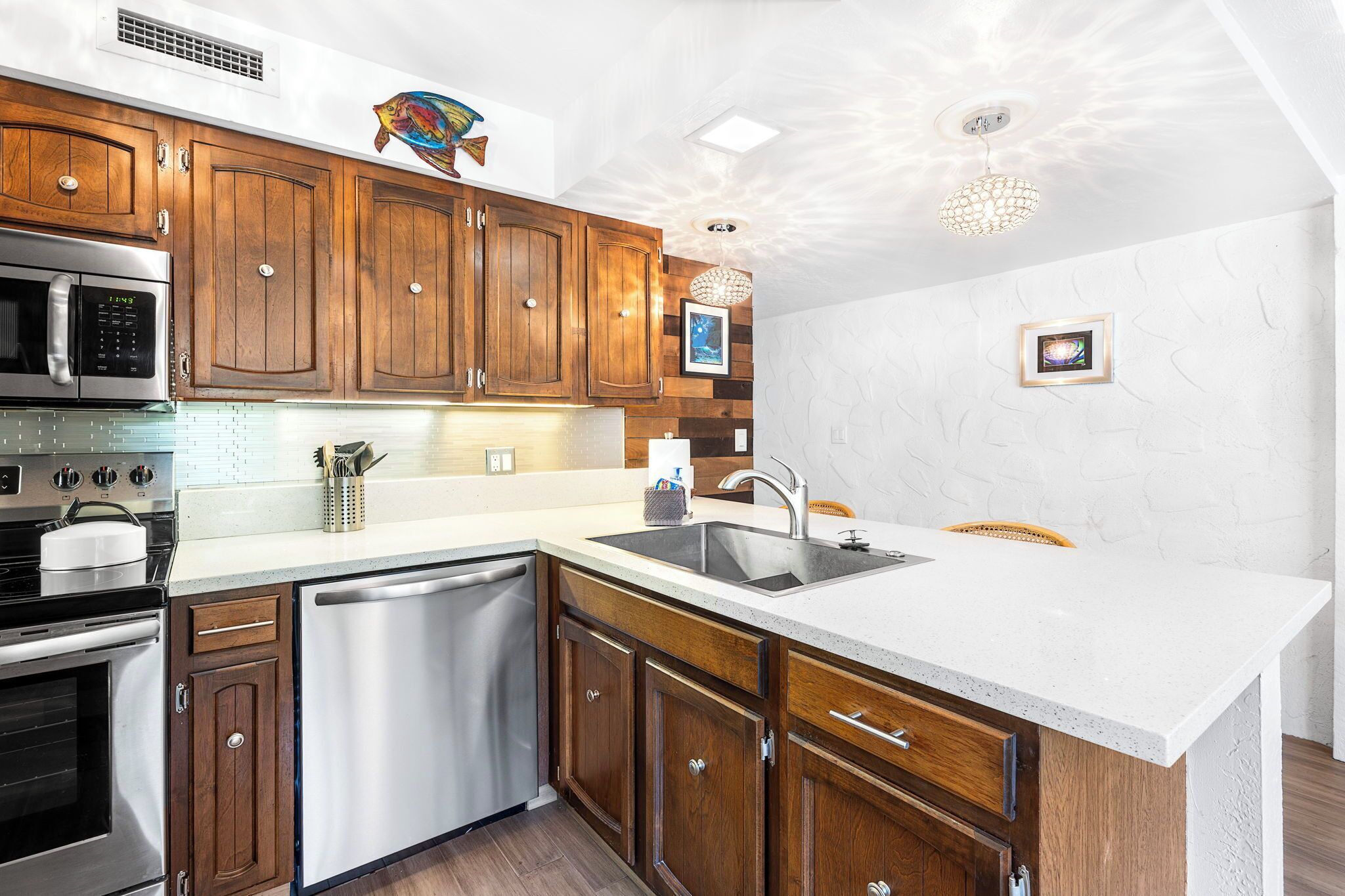 A modern kitchen with wooden cabinets, stainless steel appliances, and a white countertop.