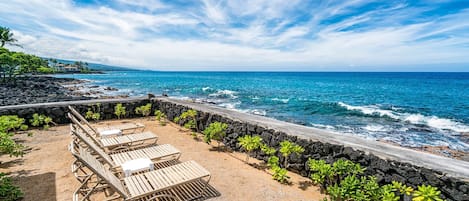 A beachside area with lounge chairs and a stone wall overlooking the ocean.