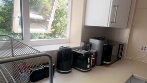 A compact kitchen with a window, a toaster, a coffee maker, and a microwave.