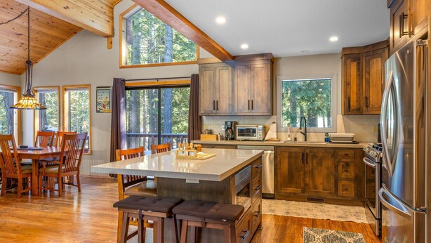 A spacious kitchen with wooden cabinets, a large island, and a stainless steel refrigerator.