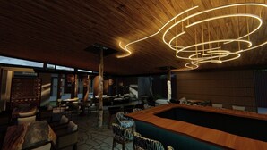 A modern indoor pool area with wooden ceiling and walls, surrounded by seating and tables. - Royal Grand Resorts (Quepos)