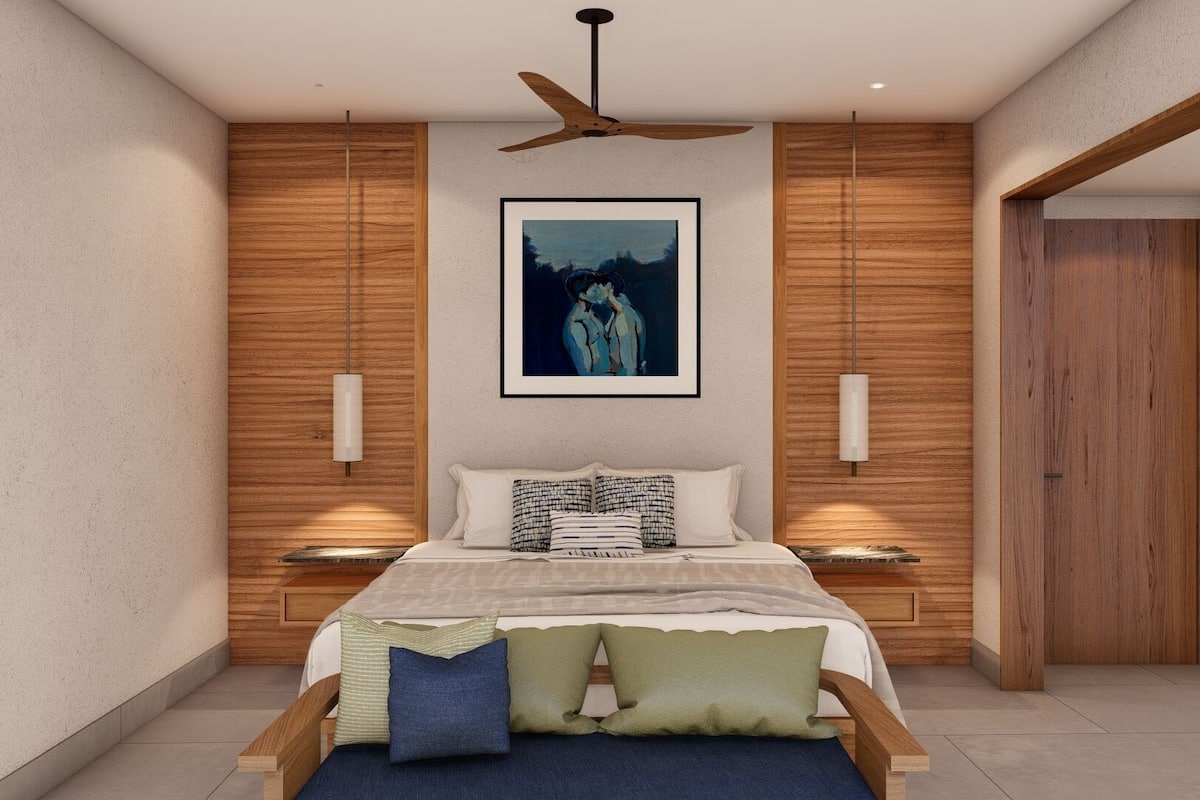 A modern bedroom with a wooden headboard, a ceiling fan, a framed artwork, and a bedside table with a lamp.