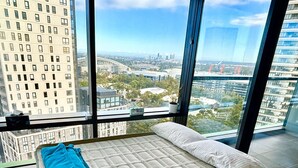Ein modernes Schlafzimmer mit großem Fenster und Blick auf die Stadt.
