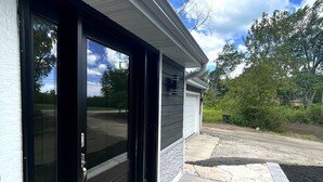 A modern building with a black door, a garage, and a well-maintained driveway.