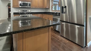 A modern kitchen with wooden cabinets, stainless steel appliances, and a granite countertop.