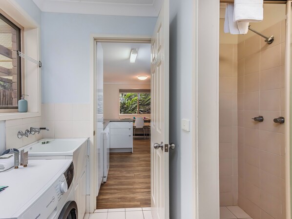 A modern bathroom with a large mirror, a white sink, and a built-in washing machine.