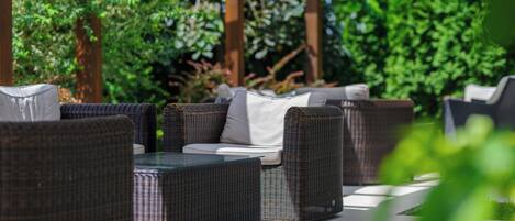 An outdoor seating area with wicker furniture and a pergola structure.