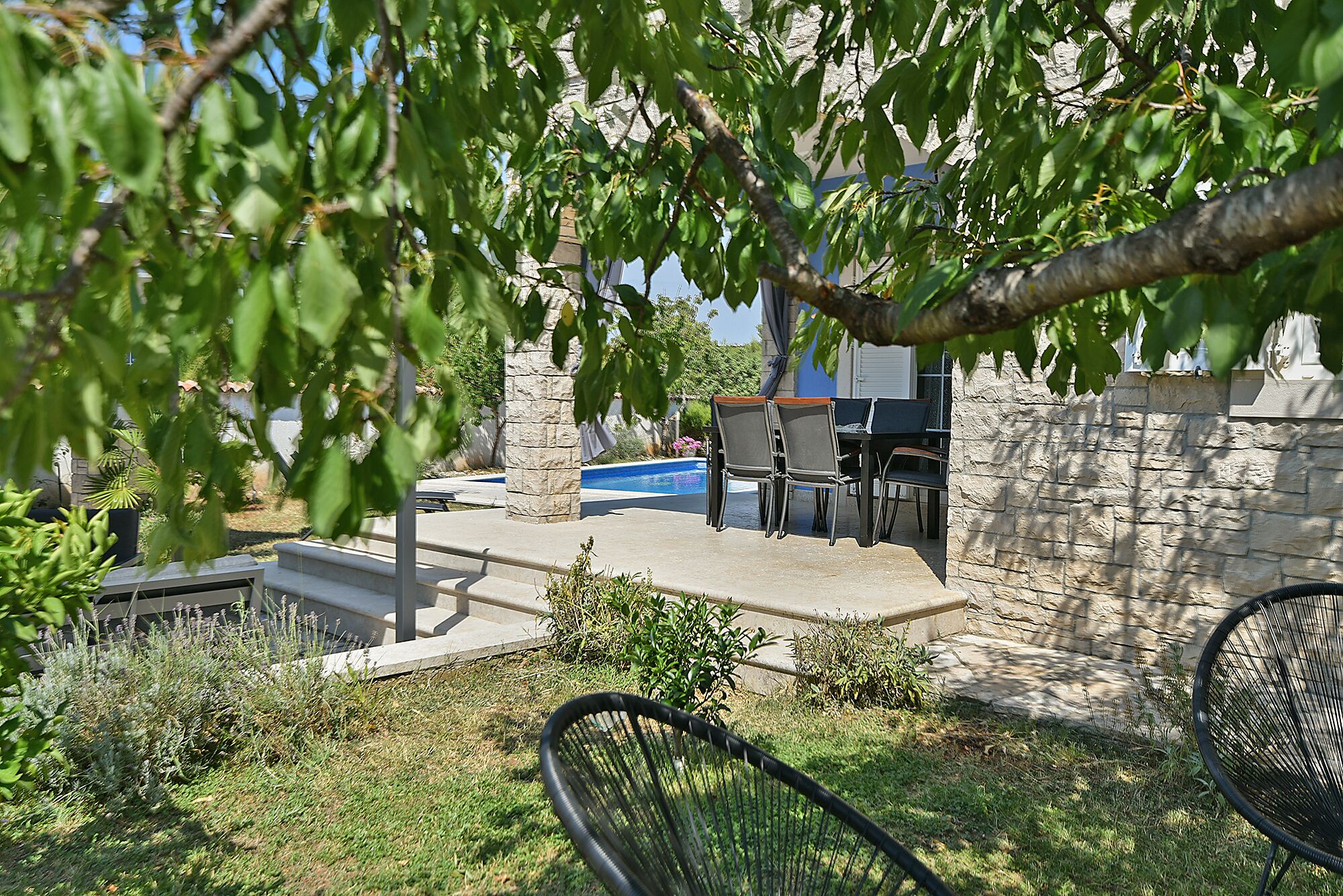 Un patio con piscina, muros de piedra y mobiliario exterior.