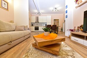 A modern living room with a sofa, a wooden coffee table with a plant, and a TV stand with decorative items.