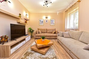 A living room with a TV, two sofas, a coffee table, and wall-mounted lights.
