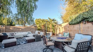 Un patio exterior con un conjunto de sofá, sillas y una mesa redonda con un centro decorativo de mosaicos.