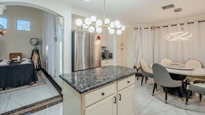 Una cocina moderna con encimeras de granito, un refrigerador de acero inoxidable y un comedor con una mesa redonda y sillas.