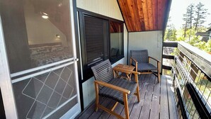 A wooden deck with two wicker chairs and a small table, overlooking a forested area. - Out of Office: Cozy A-frame cabin in the pines near trails and adventure! (Munds Park)