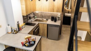 Una cocina compacta con armarios de madera, un lavamanos de acero inoxidable y un lavavajillas.