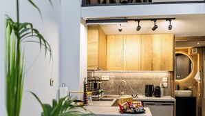 Una cocina moderna con armarios de madera, una isla central con taburetes y una lámpara colgante.