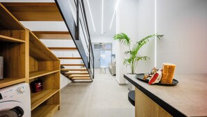 Una cocina moderna con estantes de madera, lavadora, una planta y un mostrador con pan.