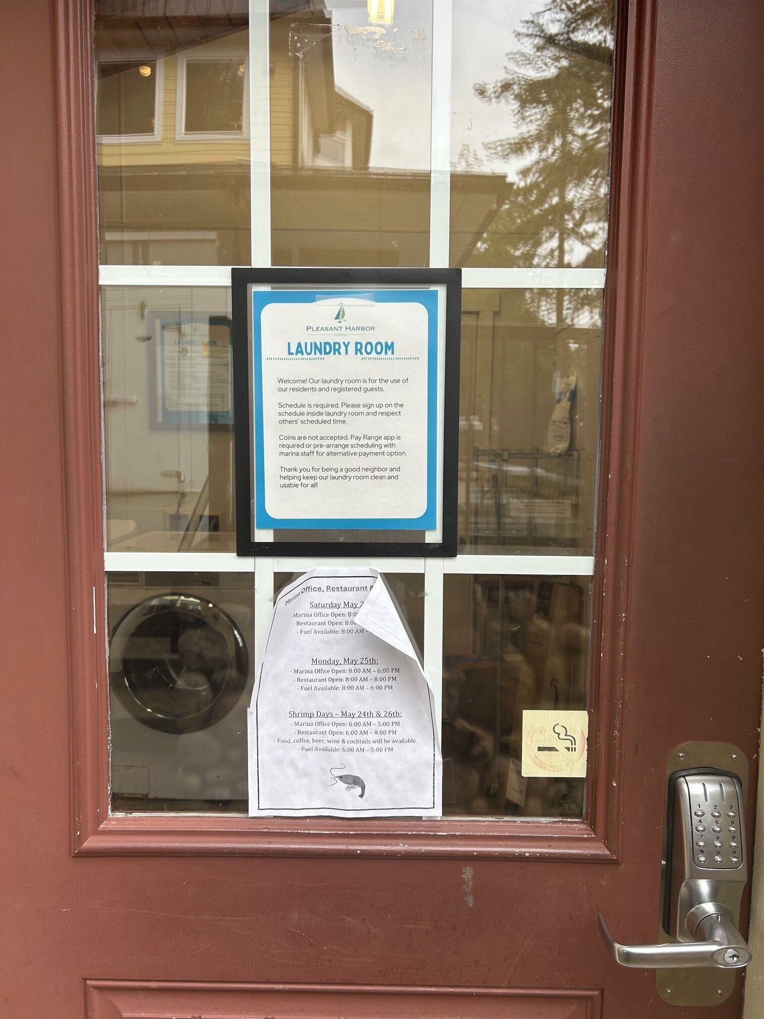 Eine Tür mit Hinweisschild für den Waschraum, ein Fenster mit einer Waschmaschine und ein Klingelgerät mit Tastatur.