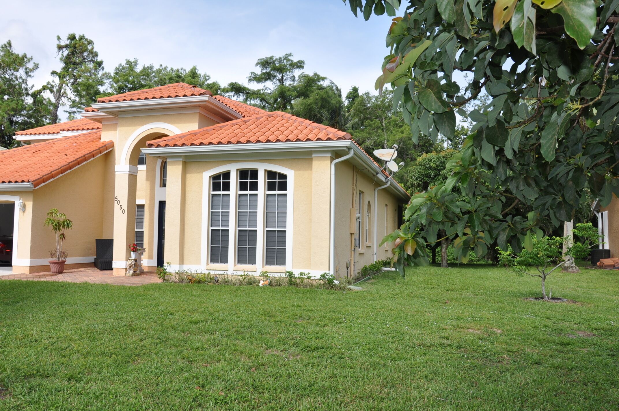 Une maison à deux étages, avec un toit recouvert de tuiles rouges, de grandes fenêtres et une pelouse bien entretenue.