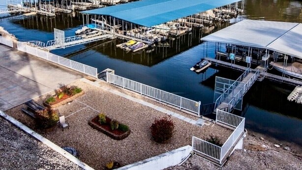 A marina with multiple docks, covered boat storage areas, and a small building with a covered deck. - Top Rated, Waterfront Condo at 19MM Amazing views! Prime location! Boat slip! (Osage Beach)