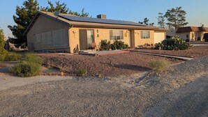 A single-story house with a sloped roof, solar panels, and a covered patio area. - Cozy 1-bedroom apartment, WiFi, AC, Views! Wildlife! In charming Pahrump (Pahrump)