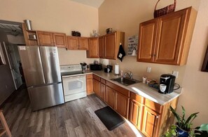 A compact kitchen with wooden cabinets, stainless steel appliances, a coffee maker, and a sink. - Cozy 1-bedroom apartment, WiFi, AC, Views! Wildlife! In charming Pahrump (Pahrump)