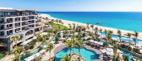 Resort com várias piscinas, uma praia e um prédio grande com varandas.