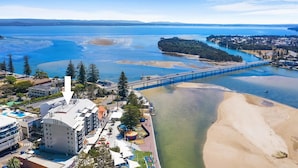 A coastal area with a bridge, beach, and buildings with balconies. - The Entrance Waterfront Apartment 505 (The Entrance)